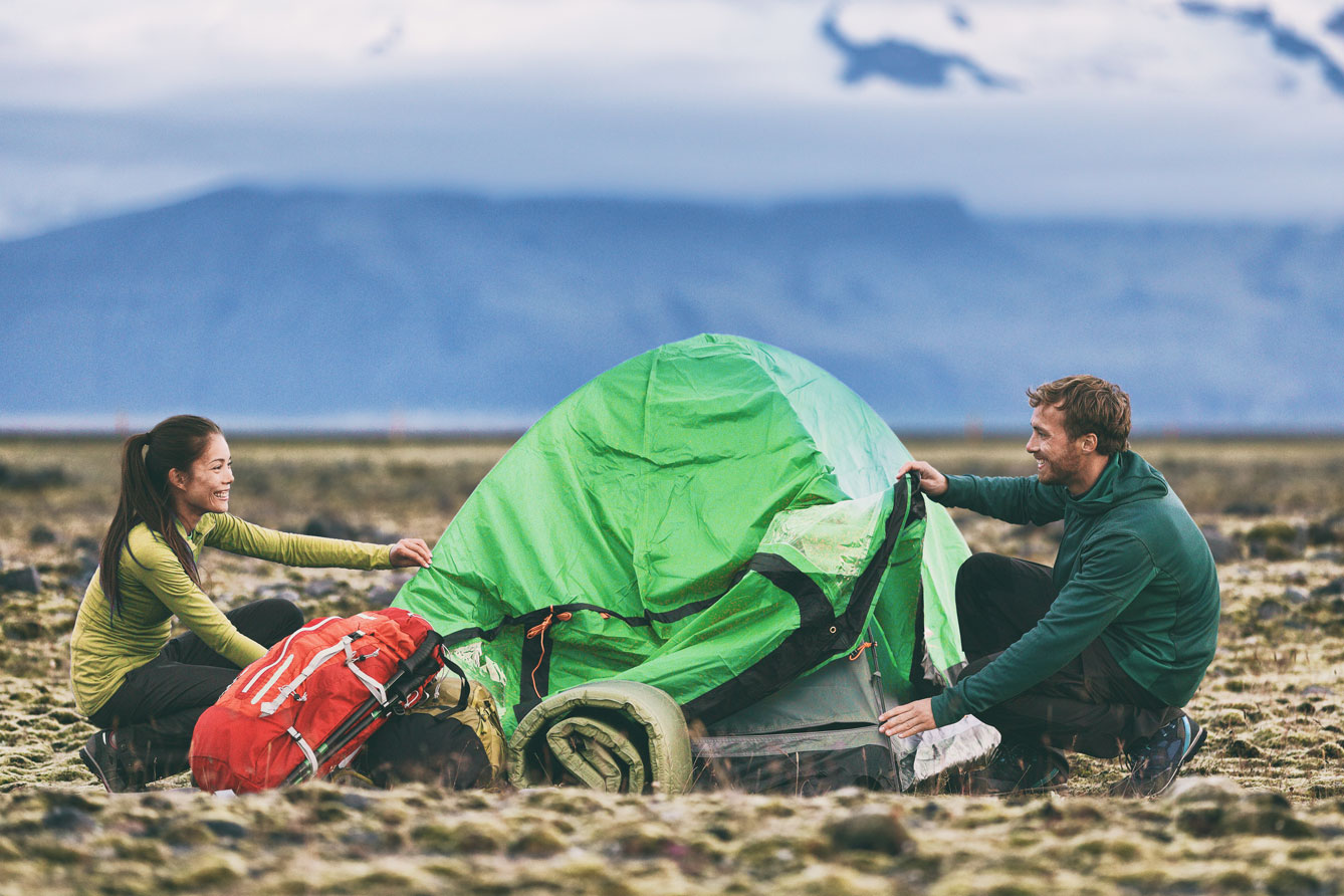 Couple setting up tent in wilderness