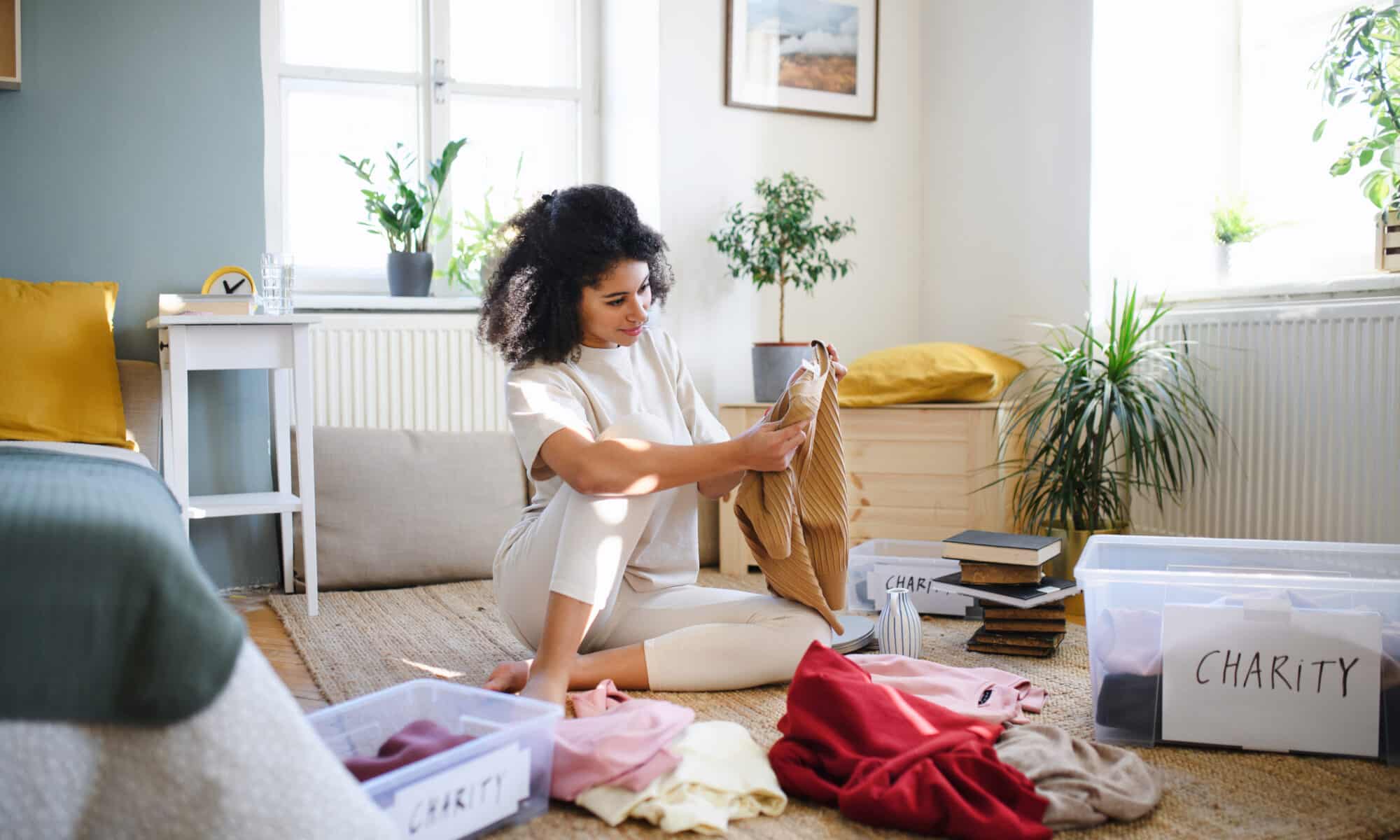 Young woman sorting wardrobe indoors at home
