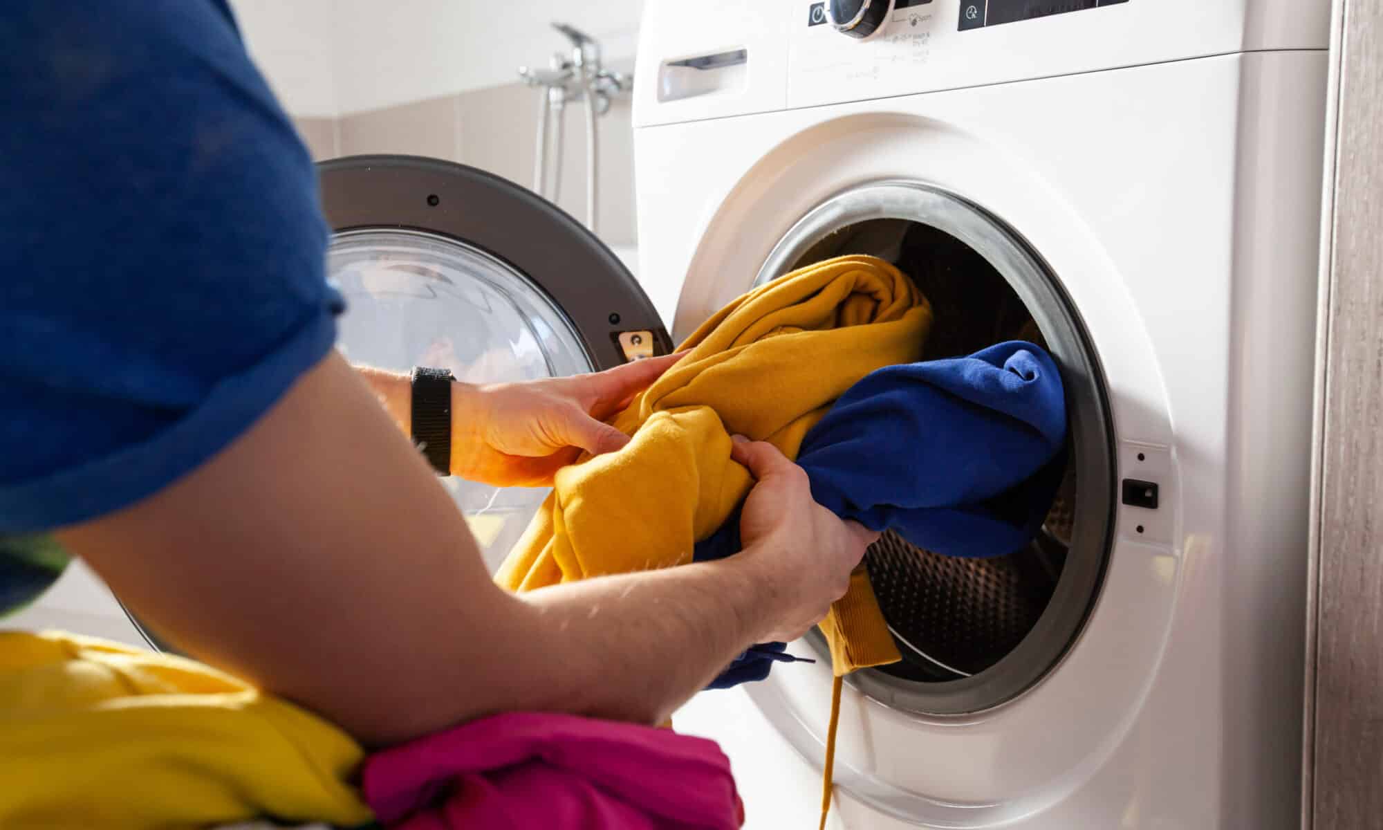 Man loading the washer dryer with clothes