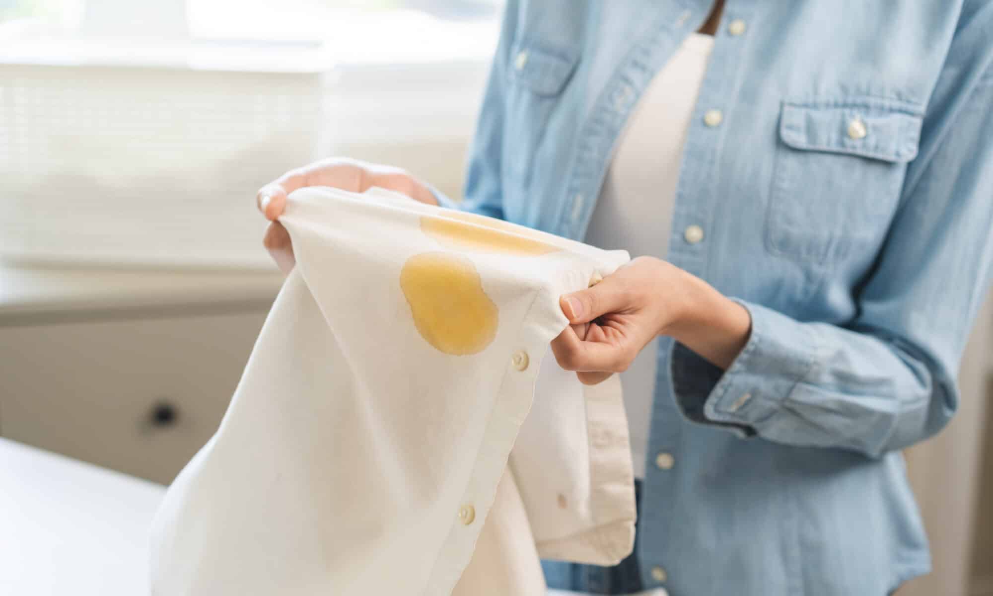 Young woman holding white shirt showing stain,
